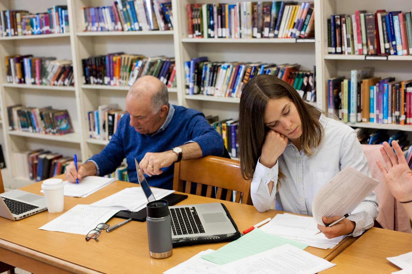 Two teachers studying materials, with the one on the left taking notes